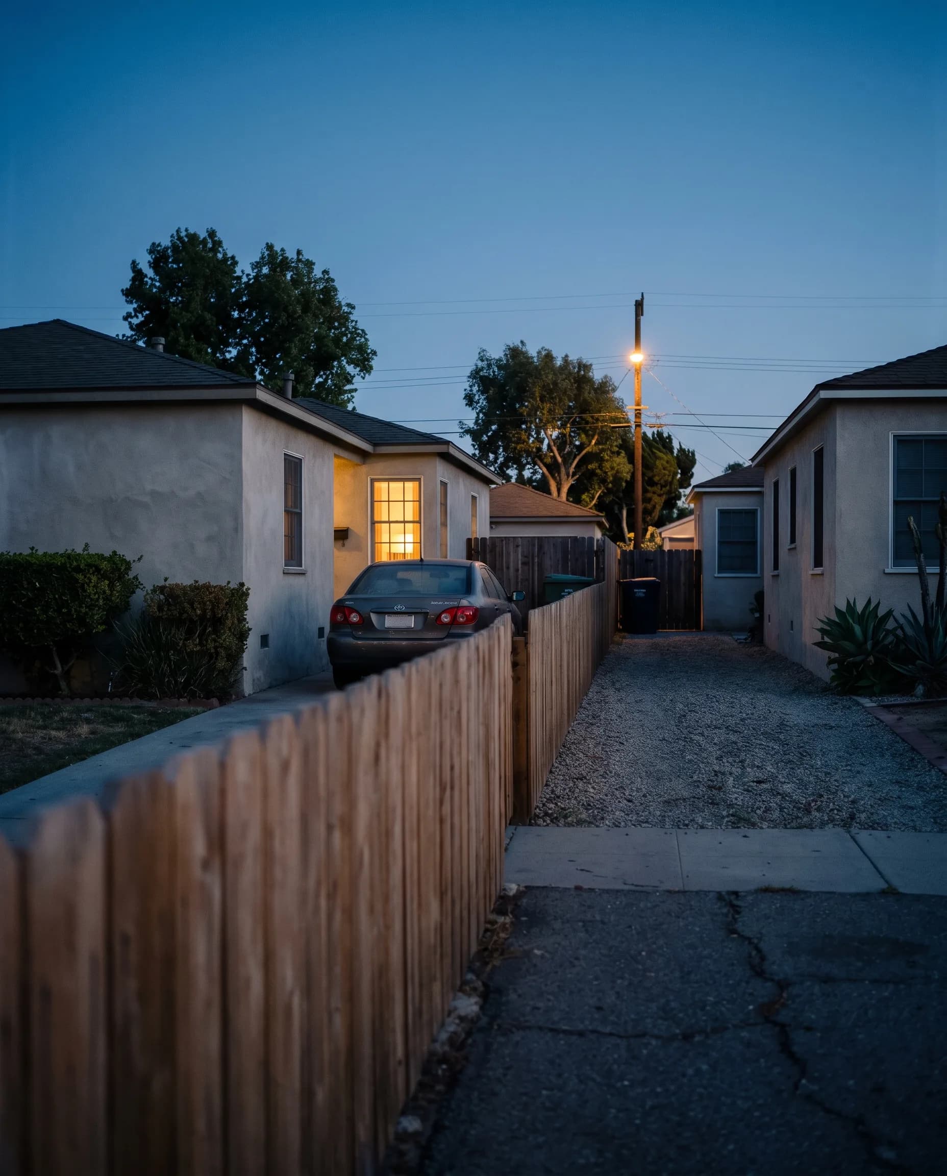A quiet residential street with houses and parked cars at dusk